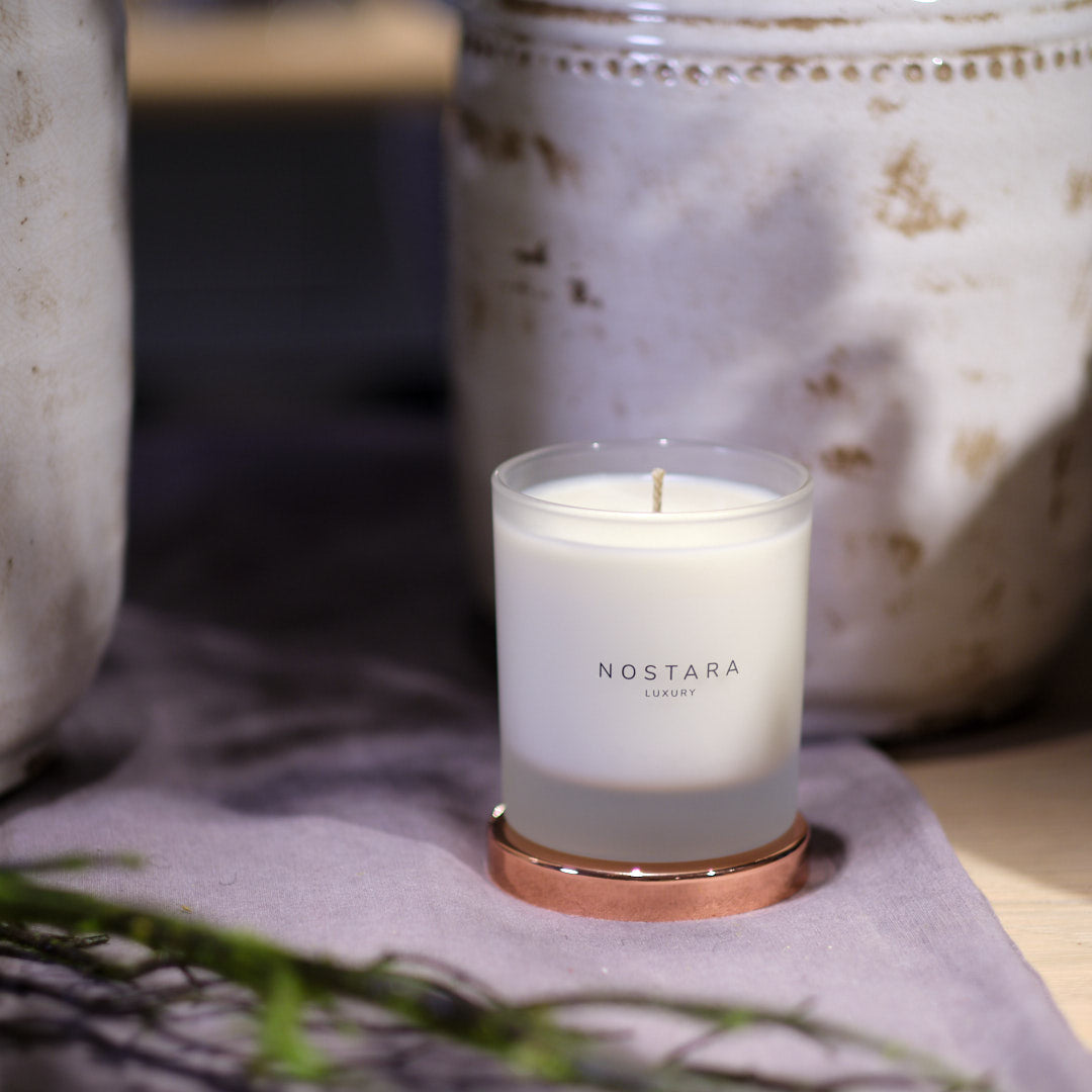 Nostara scented candle with rose gold lid on decorated table